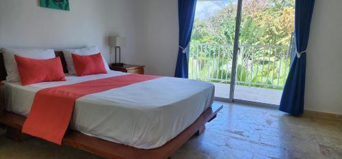 a bedroom with a bed with red pillows and a large window at Bella Villa Roomy apartment at 5 min walk to the beach in Las Galeras