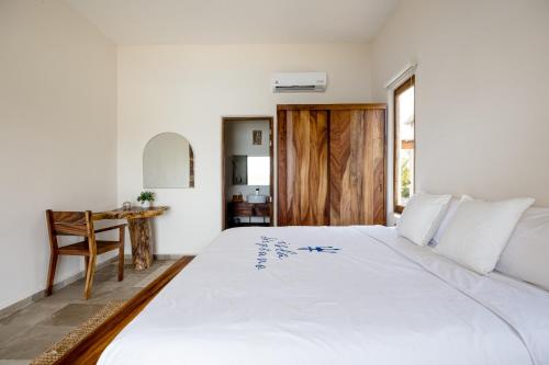 a bedroom with a large white bed and a table at Isla Neptuno in Puerto Escondido
