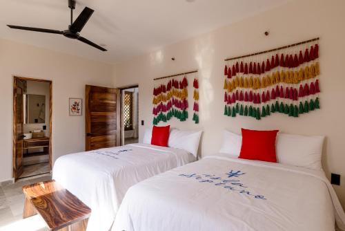 two beds with white sheets and red pillows in a room at Isla Neptuno in Puerto Escondido