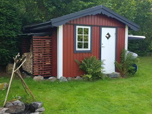 a red and white shed in a yard at 4 star holiday home in Olofström-By Traum in Olofström