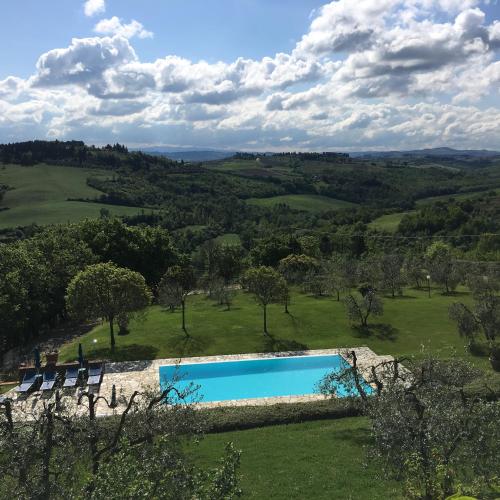a swimming pool in a field with chairs and trees at Podere Casanova in Montespertoli