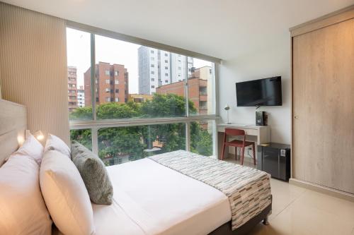 a bedroom with a bed and a large window at Hotel Suite Comfort in Medellín
