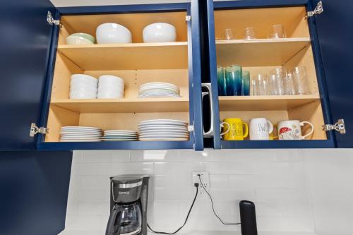 a kitchen with blue cabinets with plates and cups at Historic Home with Modern Upgrades - Prime Downtown Location in Fort Pierce