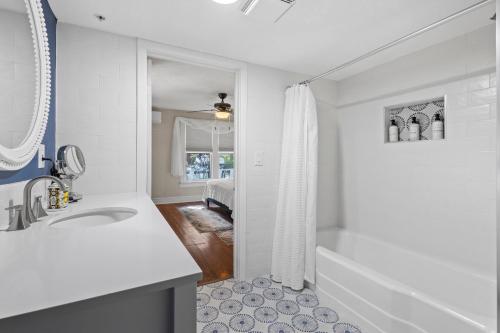 a white bathroom with a tub and a sink at Historic Home with Modern Upgrades - Prime Downtown Location in Fort Pierce
