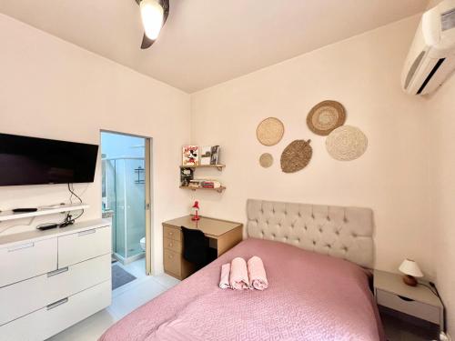 a bedroom with a pink bed and a television at Apartamento pertinho da praia e do metrô in Rio de Janeiro
