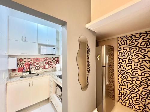 a kitchen with white cabinets and a stainless steel refrigerator at Apartamento pertinho da praia e do metrô in Rio de Janeiro