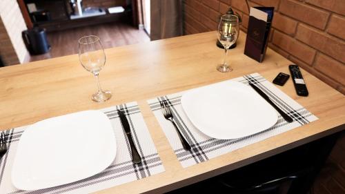 a table with two white plates and wine glasses on it at Chalé Mirante da Serra Sapucaí-Mirim in Sapucaí-Mirim