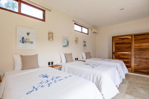 two beds in a room with white walls and windows at Isla Neptuno in Puerto Escondido