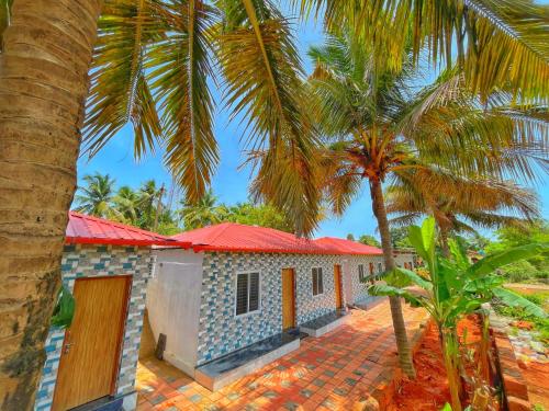 a house with a red roof and two palm trees at Shri Eshwari Homestay Murdeshwar in Māvalli