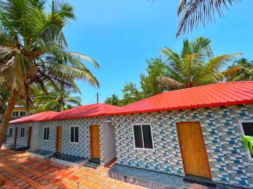 a building with a red roof and palm trees at Shri Eshwari Homestay Murdeshwar in Māvalli
