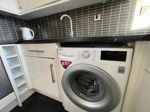 a washing machine in a kitchen with a sink at Golden Oak Two bed Apartment in Erith