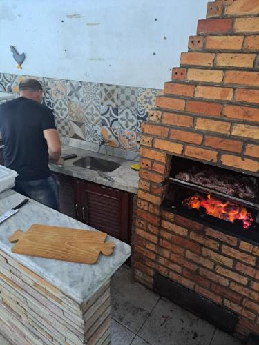un hombre parado en una cocina con un horno de ladrillo en casatemporadabelem, en Belém