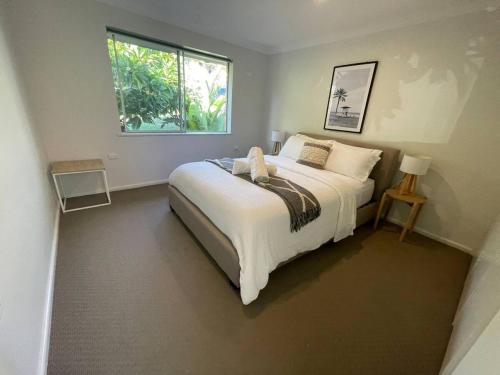 a bedroom with a large white bed with a window at Sea Salt One Burgess Beach in Forster