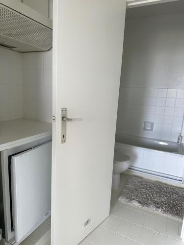 bagno bianco con servizi igienici e porta di Studio Knokke-Heist a Knokke-Heist