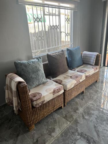 a wicker couch in a living room with a window at Inala Urban Guesthouse in Bulawayo