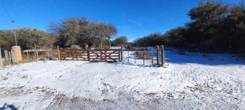 a snow covered field with a fence and trees at Portezuelo de árboles in Panaholma