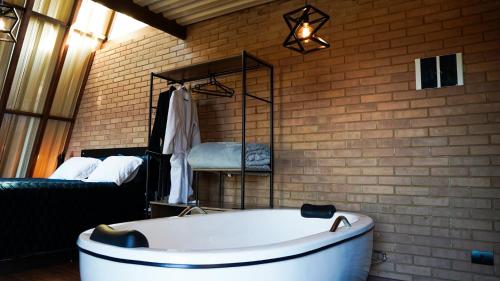 a bath tub in a room with a brick wall at Chalé Mirante da Serra Sapucaí-Mirim in Sapucaí-Mirim