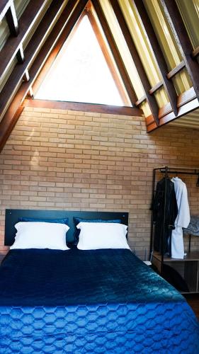 a bedroom with a blue bed with a large window at Chalé Mirante da Serra Sapucaí-Mirim in Sapucaí-Mirim