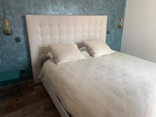 a bedroom with a white bed with two pillows at La Titou Martin in Saint-Michel-Chef-Chef