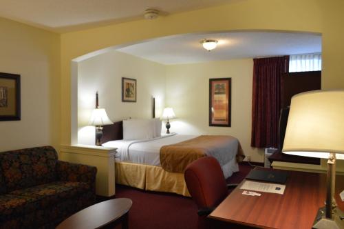 a hotel room with a bed and a chair and a table at Opal Hotel & Suites in Orlando