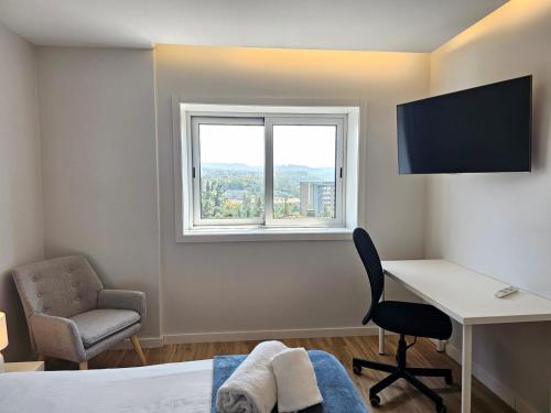 a room with a desk and a chair and a window at Guimarães Downtown 2 by LuxiStay in Guimarães