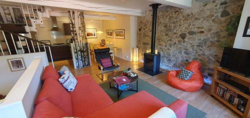 a living room with a red couch and a fireplace at Les Quatre Saisons in Montaillou