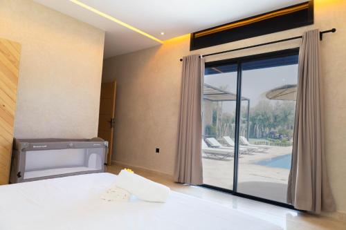 a bedroom with a bed and a large glass window at Villa Privée de Luxe avec Piscine et Vue sur l Atlas Marrakech in Aghmat