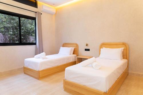 two beds in a room with a window at Villa Privée de Luxe avec Piscine et Vue sur l Atlas Marrakech in Aghmat