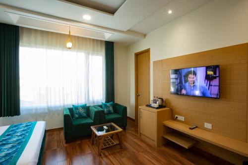 a hotel room with a bed and a couch and a tv at Hotel Popular Suites in New Delhi