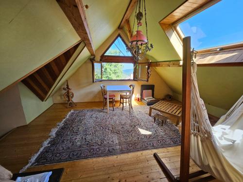 an attic room with a table and chairs and a window at Bienvenue chez jacquou Chambre d'hote cher l'habitant in Aubure