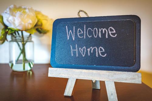 a welcome home sign on a table with a vase of flowers at Creekside at Rundle Cliffs Lodge in Canmore