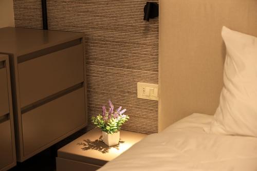 a bedroom with a bed and a plant on a night stand at Giselle Escape in Tirana