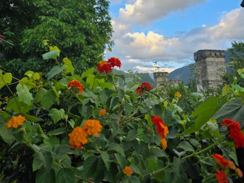 a garden with flowers in front of a castle at Ailama Guesthouse in Mestia
