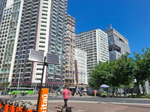a person riding a bike in a city with tall buildings at Apartamento Metrô Carioca - Centro Rio in Rio de Janeiro
