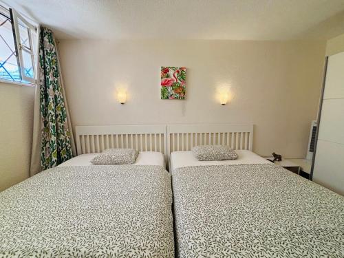 two twin beds in a room with a window at Neptuno Beachfront Retreat with smart TVs and Terrace in Puerto de Santiago