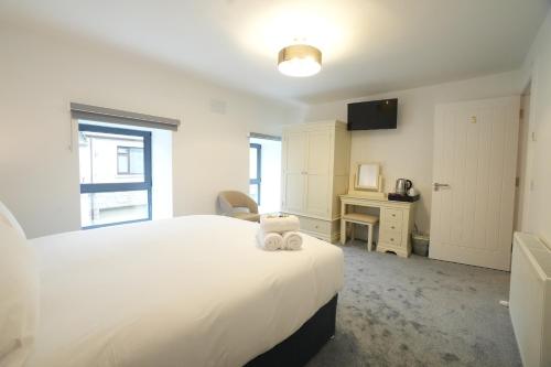 a bedroom with a large white bed and a desk at The Lodge in Dunmore
