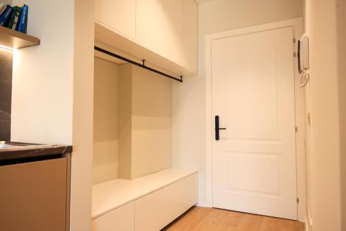 a kitchen with white cabinets and a white door at Giselle Escape in Tirana