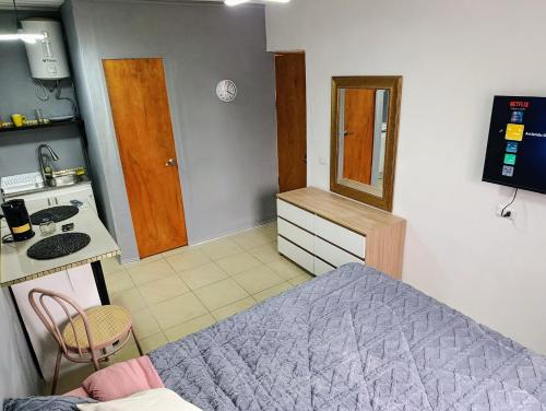Una pequeña habitación con una cama y una cocina. en Habitación Studio con baño privado, en Iquique