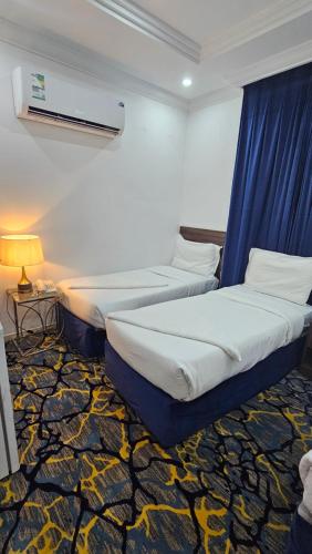 two beds in a hotel room with a blue curtain at Luluat Al Badaie Hotel in Makkah