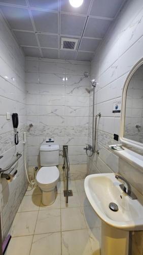 a white bathroom with a toilet and a sink at Luluat Al Badaie Hotel in Makkah