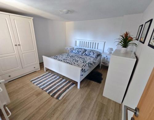 a bedroom with a white bed and a white cabinet at Penzión Tatroom in Poprad