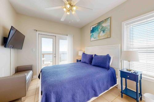 a bedroom with a blue bed and a ceiling fan at Midsummer Solstice in Dauphin Island