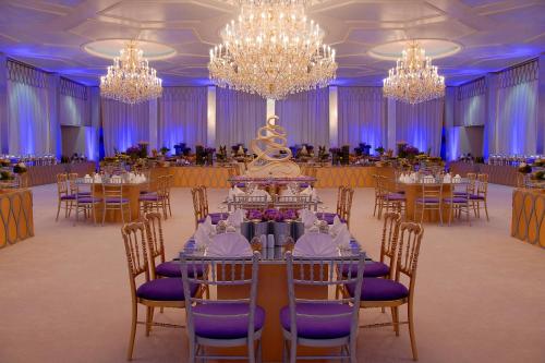a banquet hall with tables and chairs and chandeliers at Sheraton Kuwait, a Luxury Collection Hotel, Kuwait City in Kuwait