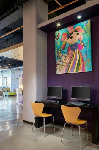 a wall with two chairs and a painting on a wall at Aloft Cancun in Cancún