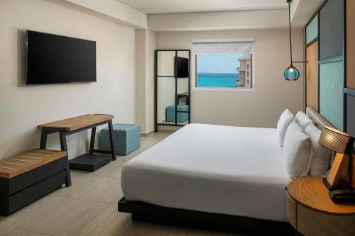 a bedroom with a bed and a table and a tv at Aloft Cancun in Cancún