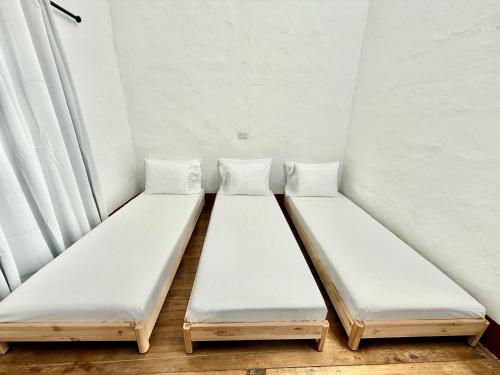 two beds in a room with white walls at Elegant Colonial Walkable Casa in Jericó