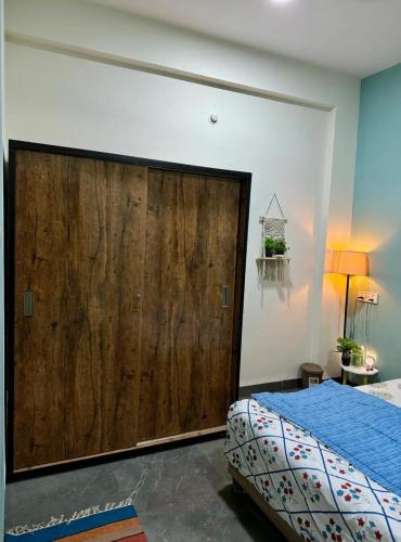 a bedroom with a large wooden door next to a bed at Your Home in Indore