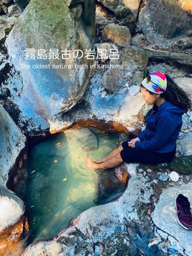 a woman sitting on a rock in a pool of water at まるしっぽ邸-Marushippotei-連泊20パーセントOFF!Onsen,BBQ,hammock,national park,home theater in Murautsuri