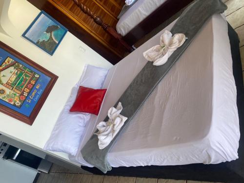 a bed with white sheets and flowers on it at Hotel Manuel Antonio Inn in Quepos