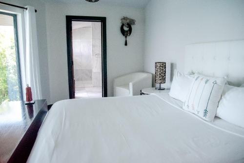 a white bedroom with a large white bed and a window at Tamarind Hills Resort & Villas in Johnsons Point